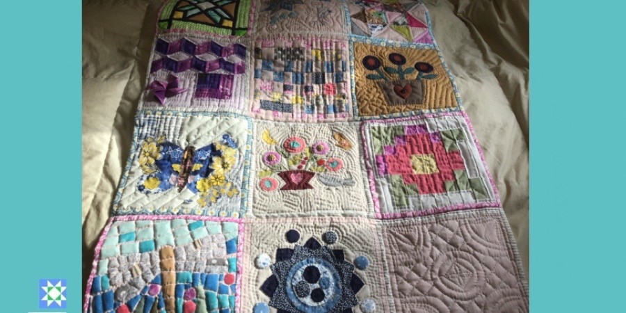 Quilt Regazo hecha con 12 bloques hechos con el patchwork sobre una cama